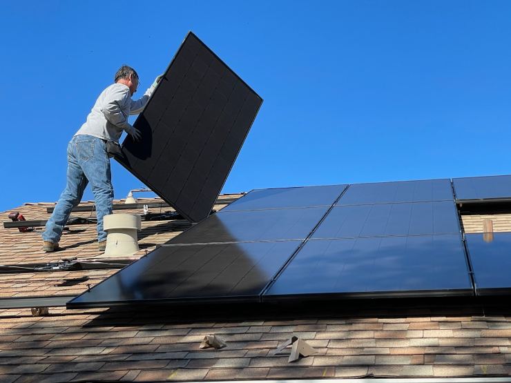 Operatore installa pannello fotovoltaico sul tetto di una casa