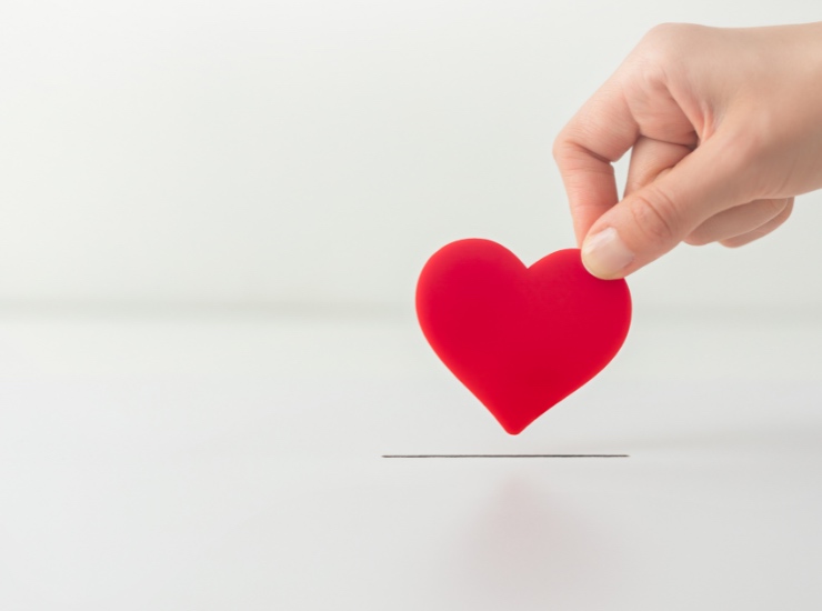 Una persona infila un cuore stilizzato nella fessura per donazioni