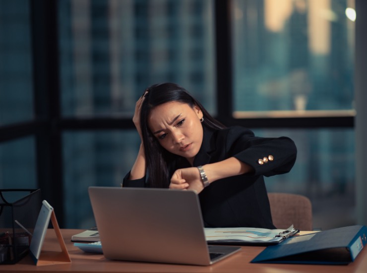 Una ragazza disperata guarda l'orologio al lavoro