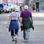 Uomo e donna camminano mano nella mano, ripresi di spalle