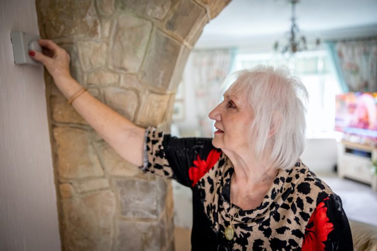 Donna regola il termostato in casa