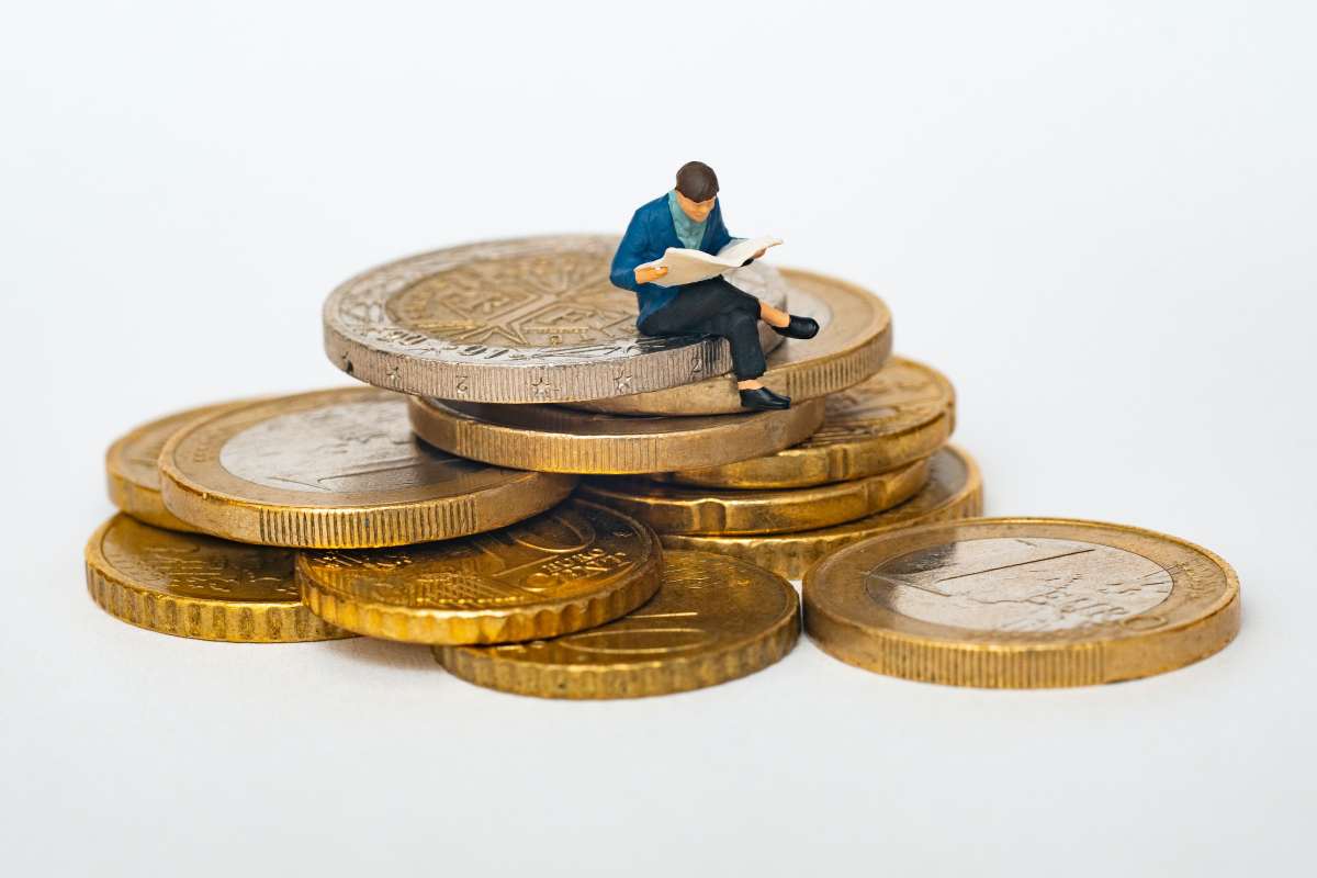 Omino di plastica seduto su monete di euro